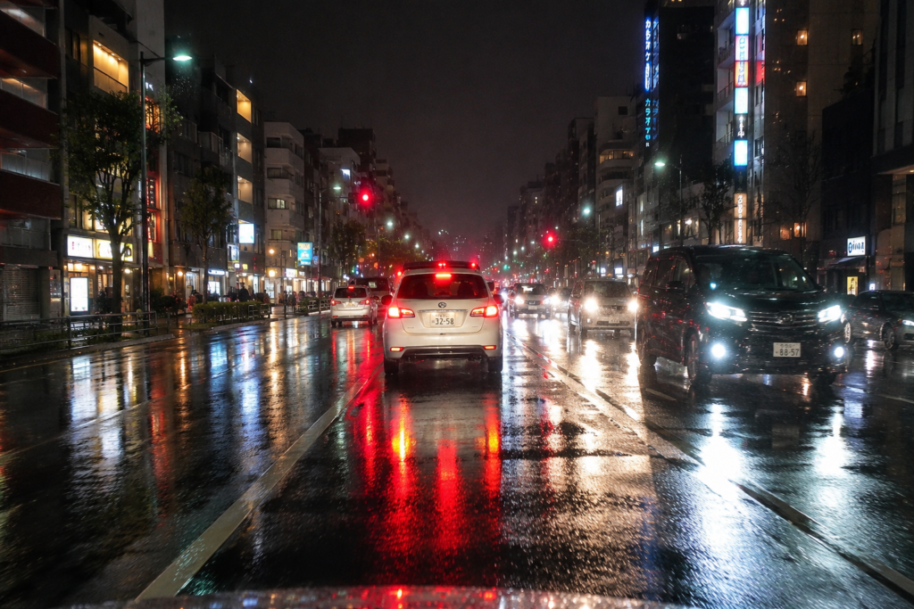 夜の雨で対向車のライトや路面の反射に注意する運転場面