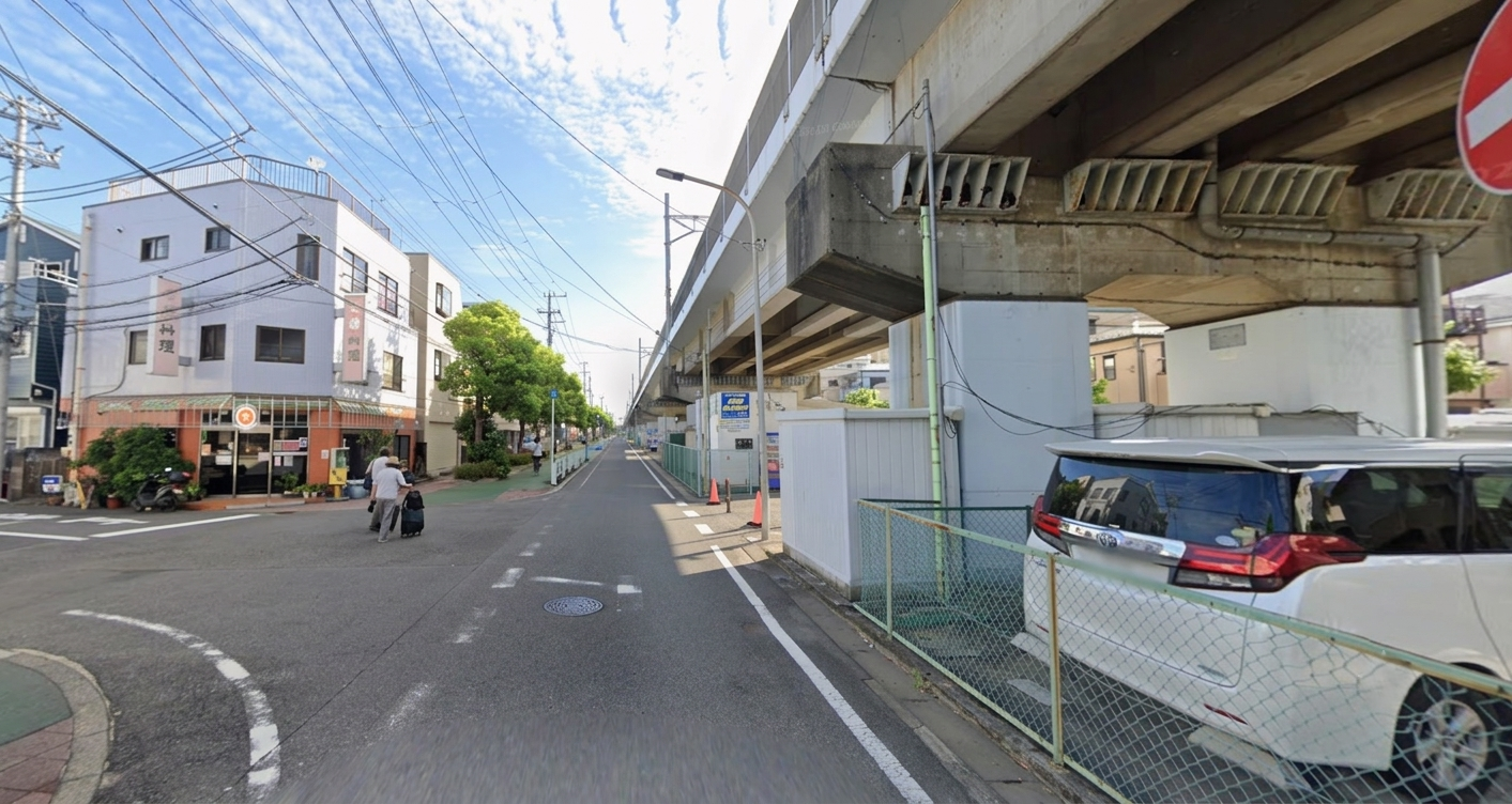 東西線の高架沿いで柱とフェンスの切れ目がある道路