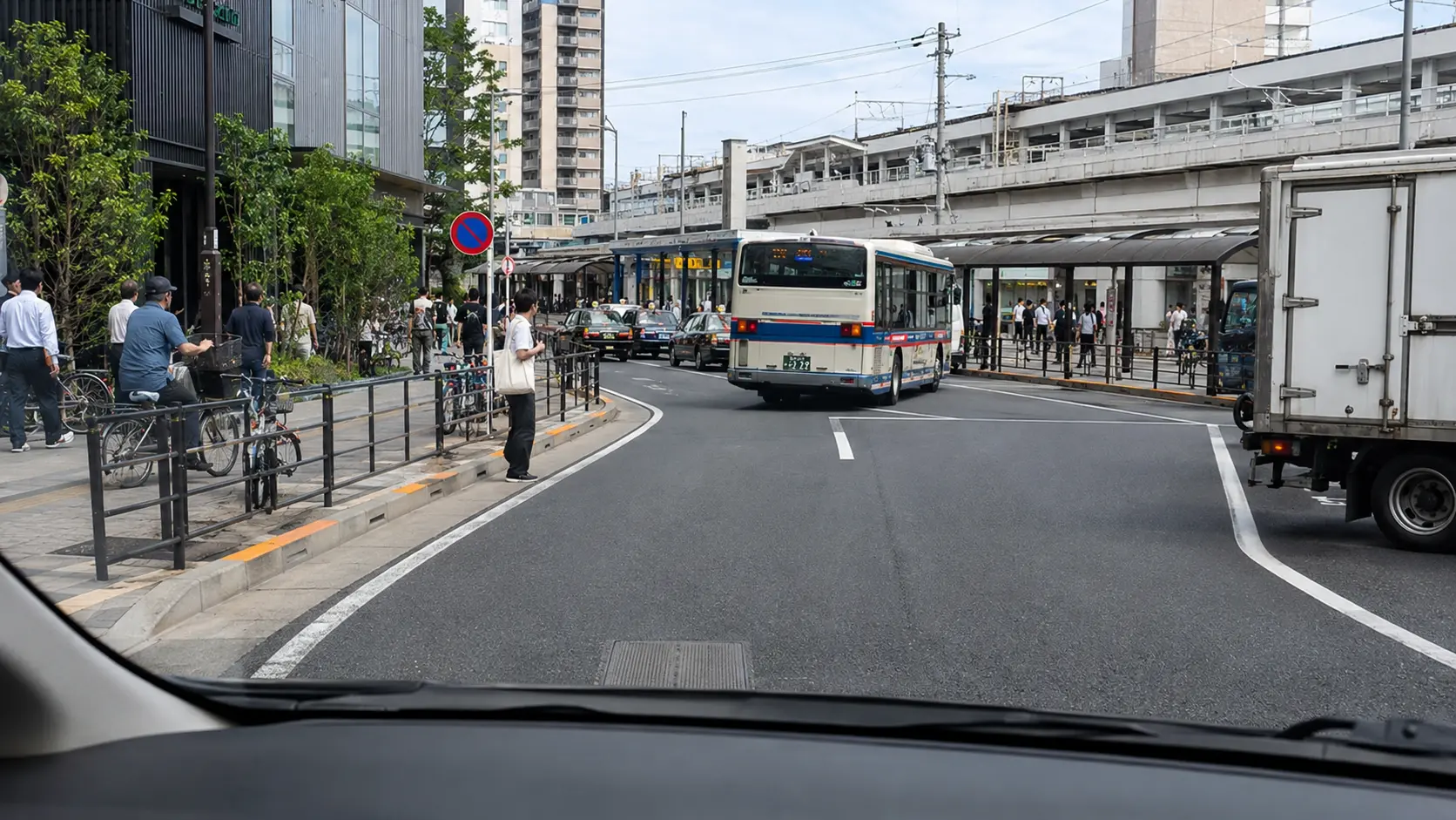 船橋駅周辺のロータリー手前を運転席から見た道路とバス、歩行者、ガードレール