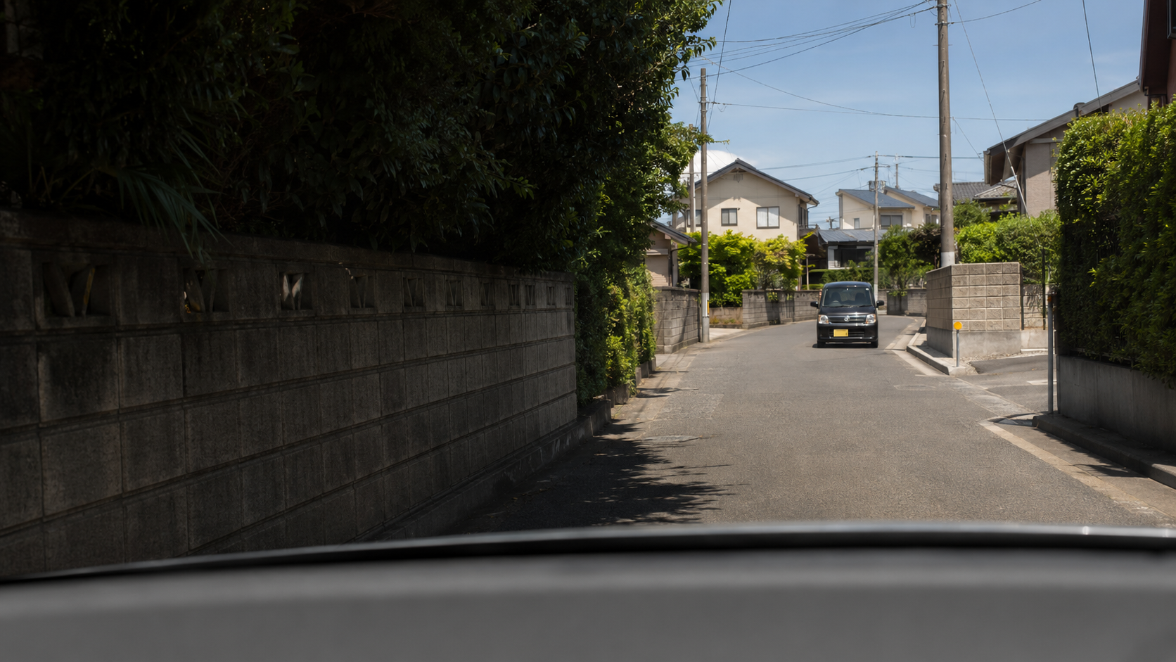 塀に囲まれた狭い住宅街ですれ違う車