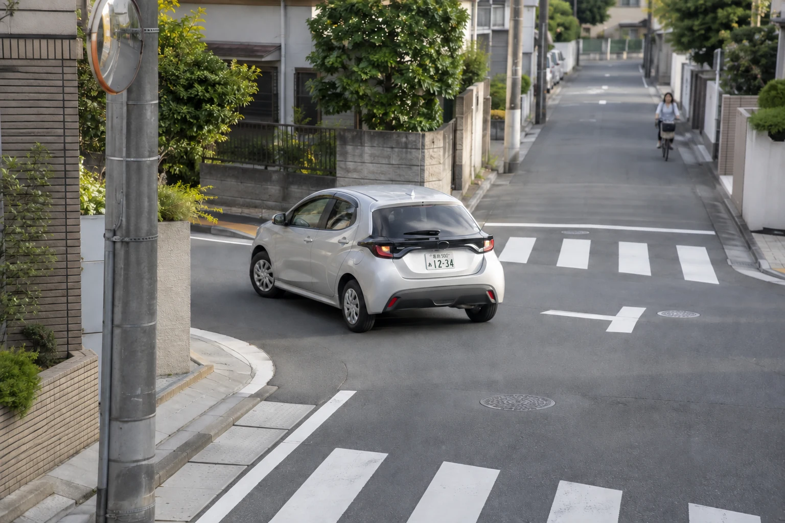 葛飾ナンバーの車が住宅街の角をゆっくり左折する様子