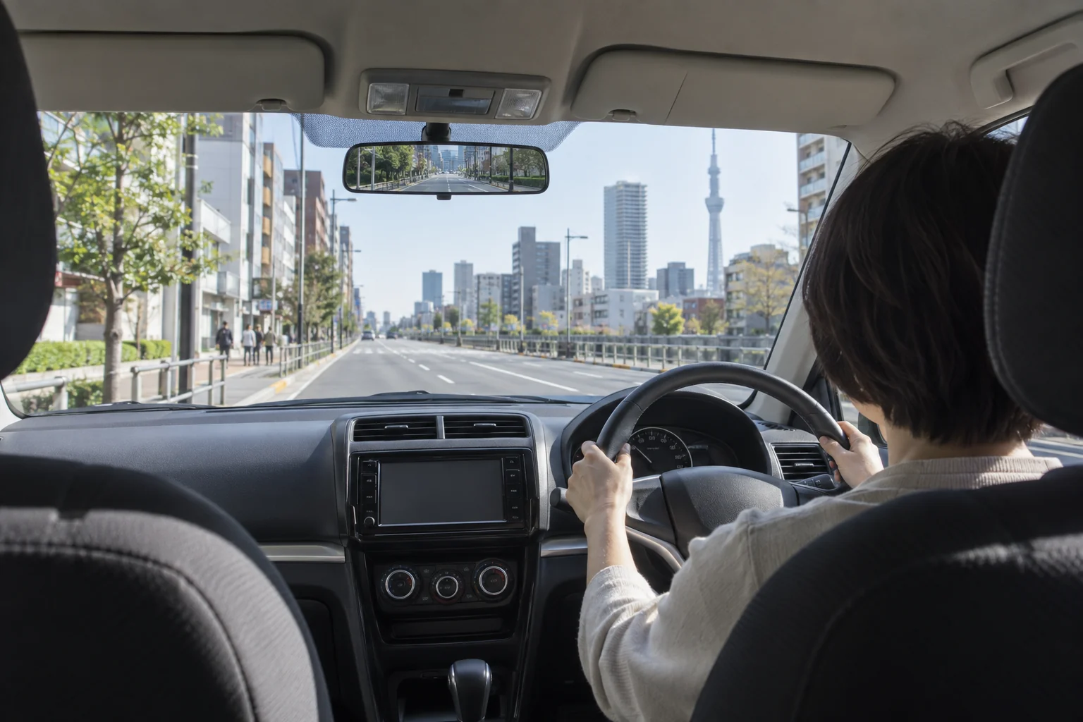 押上周辺の市街地を教習車で走る50代女性の後ろ姿