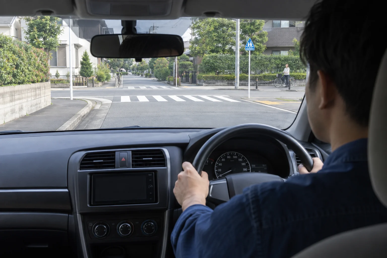 住宅街の交差点で左折前に横断歩道と自転車を確認する運転席からの視界